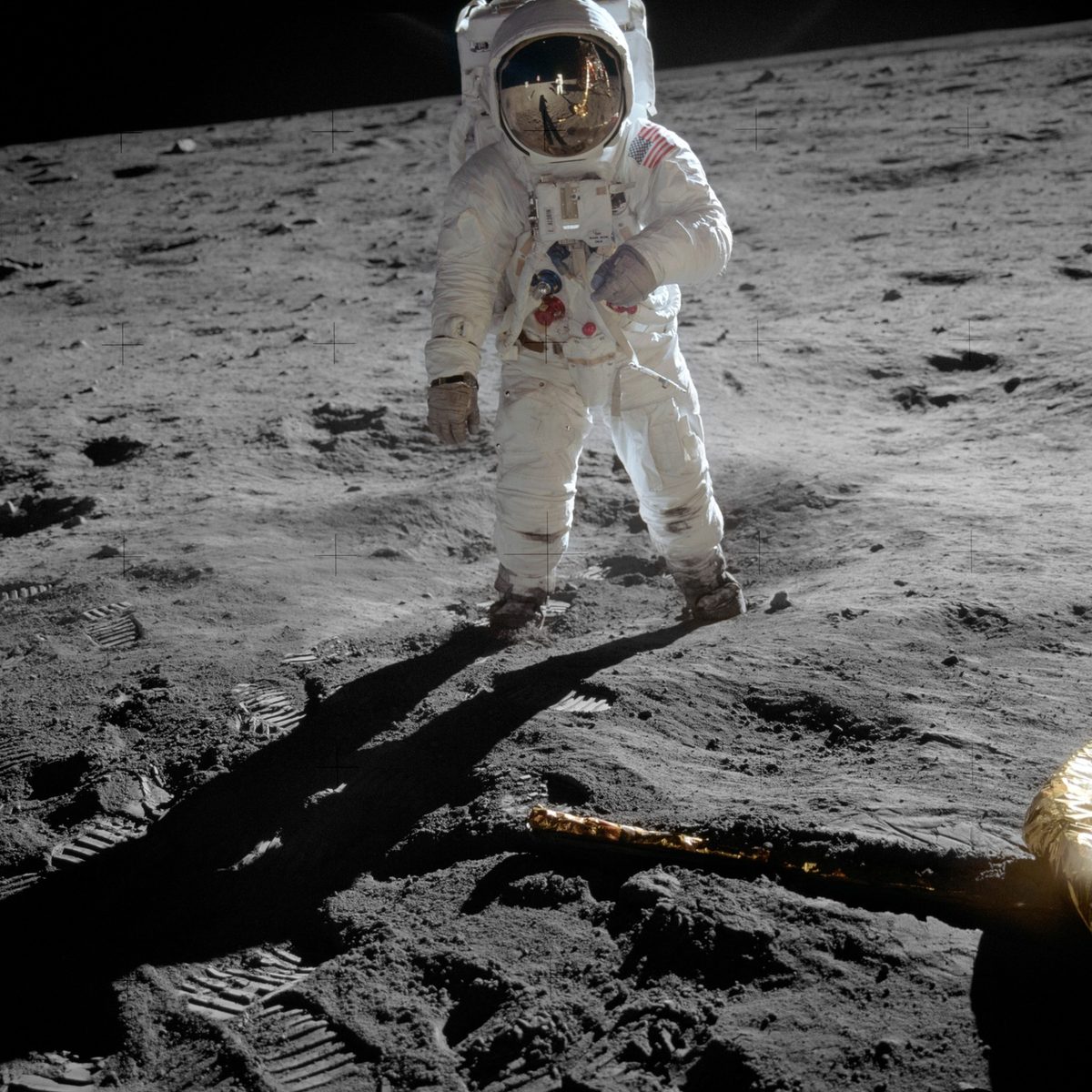Buzz Aldrin standing on the Moon during Apollo 11, his gold visor reflecting Neil Armstrong and the lunar module, boot prints in the grey dust