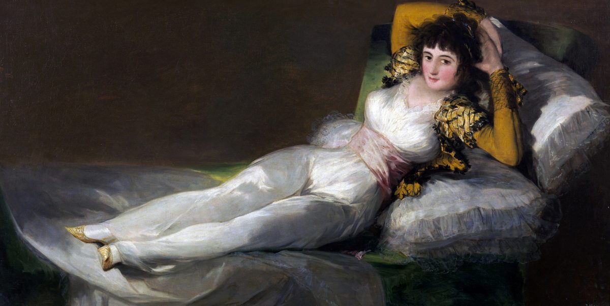 Goya's The Clothed Maja: a young woman in a white dress, gold-embroidered jacket and pink sash reclining on green cushions with her hands behind her head